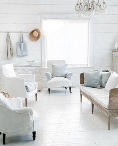 a white living room filled with furniture and a chandelier hanging from the ceiling