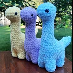 three crocheted llamas are sitting on a wooden table in the grass