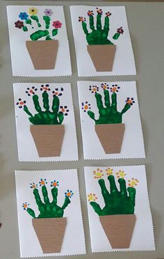 four cards with handprinted cactus in a pot on top of a table next to flowers