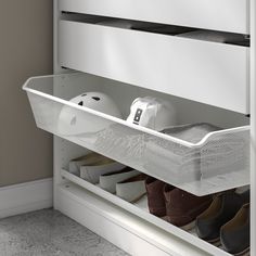 an organized shoe rack with shoes and hats in the bottom drawer, on top of a white cabinet