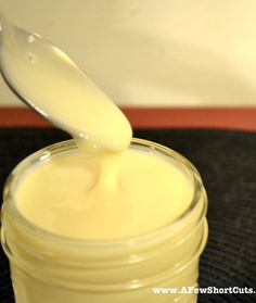 a glass jar filled with cream sitting on top of a table