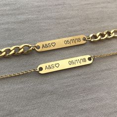 two personalized gold chain bracelets with names engraved on the side and heart charms attached to them