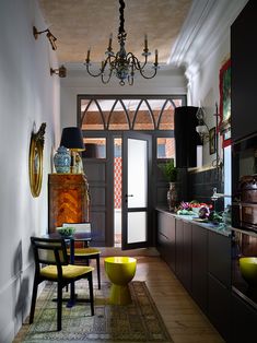 a dining room table and chairs in front of a doorway with a chandelier