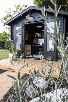 a small black shed with an open door on the outside and plants growing in it