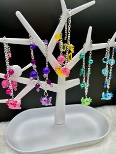 a white tree with many colorful beads hanging from it's branches on a plate