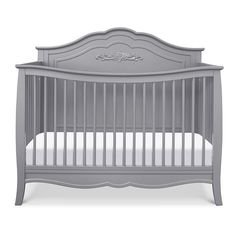 a gray crib with white sheets on it