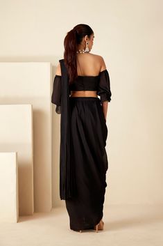 This pre-draped saree features exquisite hand-embroidered zardosi details, adding a touch of opulence to the off-shoulder style. Perfect for cocktail nights and sangeet ceremonies, it offers convenience with its pre-drape skirt saree design and back hook opening. The sheer sleeve details enhance its allure, while the luxurious georgette crepe fabric in timeless black ensures both comfort and sophistication. Make a statement at your special occasions with this stunning ensemble that effortlessly combines tradition and modernity. Black Chanderi Pre-draped Saree With Unstitched Blouse, Luxury Black Chanderi Pre-draped Saree, Festive Black Embellished Pre-draped Saree, Black Embellished Pre-draped Saree, Unstitched Black Handloom Pre-draped Saree, Cocktail Saree, Skirt Saree, Draped Saree, Cocktail Night