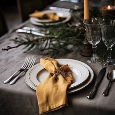 a table set with silverware, candles and napkins