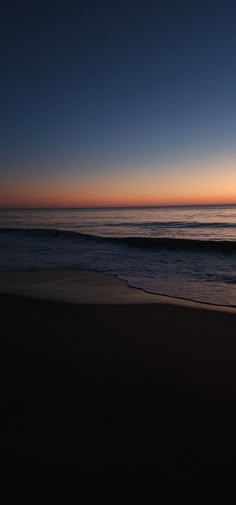 the sun is setting over the ocean with waves coming in