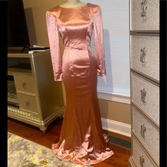 a pink dress is on display in front of a dresser with drawers and an armoire