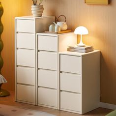 a white cabinet sitting next to a lamp on top of a table in a room