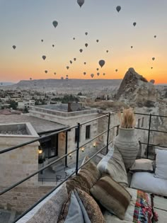 hot air balloons are flying in the sky above a rooftop area with couches and pillows