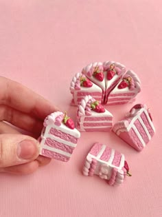 a hand is holding a miniature piece of cake with strawberries on it and other pieces are in the background