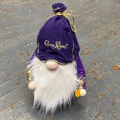 a purple and white stuffed animal wearing a purple hat with gold lettering on it's face