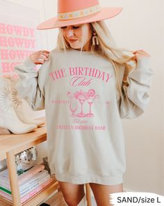 a woman wearing a pink hat and sweatshirt with the words, the birthday club on it