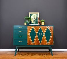 a green and gold dresser with plants on top in front of a dark gray wall