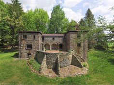 an old brick building in the middle of a forest with trees and grass around it