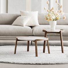 a living room scene with focus on the couch and coffee table, along with flowers