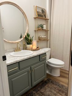 a white toilet sitting next to a bathroom sink under a round mirror on top of a wooden shelf