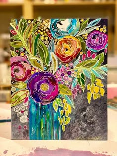 a card with flowers painted on it sitting on a table next to paintbrushes