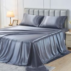 a bed with silver sheets and pillows in a room