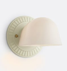 a wall light with a white shade on it's side and a gold button in the middle