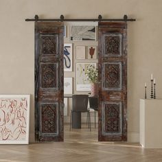 an open wooden door leading into a living room with pictures on the wall and chairs