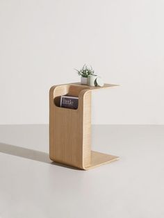 a small wooden table with a plant on top and a magazine holder in the middle