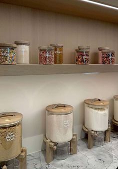 several jars and containers are lined up on the wall in a kitchen with marble flooring