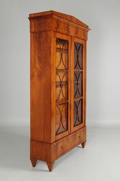 an old wooden cabinet with glass doors on the front and bottom shelves inlays