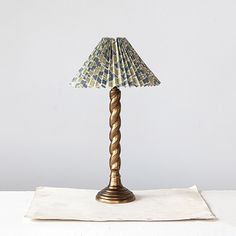 a lamp that is sitting on top of a white tablecloth with a blue and green shade