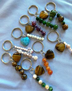 several different types of beads and charms on a white sheet with a blue cloth in the background