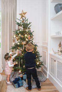 two young children decorating a christmas tree