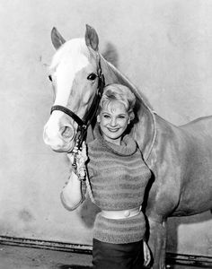 a black and white photo of a woman holding the reigns of a horse's head