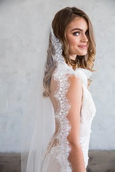 a woman wearing a wedding veil with lace on it