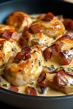 a skillet filled with chicken and bacon covered in cheese sauce on top of a wooden table