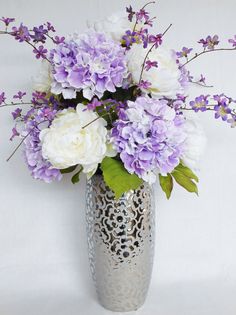 a silver vase filled with purple and white flowers