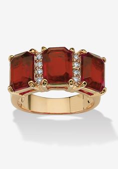 a gold ring with three red stones and diamonds on the sides, set against a white background