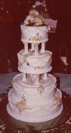 a three tiered wedding cake with flowers on the top and sides, sitting on a table