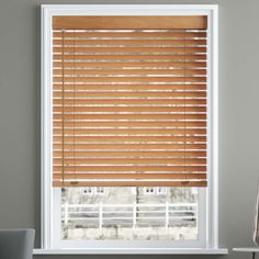 a window with wooden blinds on it and a white chair in front of the window