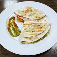 three quesadillas on a white plate with pickles