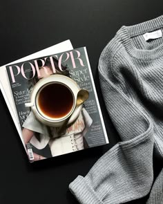 a cup of coffee sitting on top of a magazine next to a pair of pants