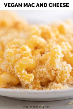 a white plate topped with macaroni and cheese covered in crumbs on top of a table