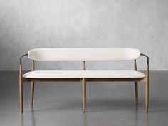 a white couch sitting on top of a cement floor next to a wooden frame bench