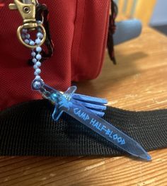 a small blue plastic object sitting on top of a wooden table next to a red bag