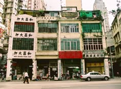 an old building with chinese writing on it's side in the middle of a city