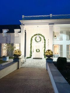 the front entrance to a large white house with wreaths on it's pillars