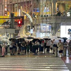 a group of people holding umbrellas standing in the rain on a city street at night