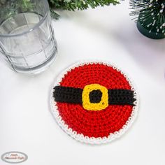 a crocheted christmas ornament on a table next to a glass of water