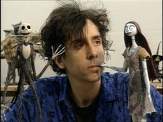 a man sitting in front of some creepy dolls